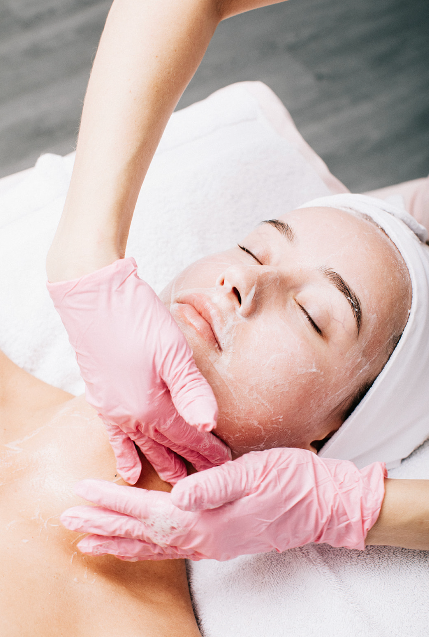 A woman undergoing a facial treatment, surrounded by calming spa elements and soft lighting.