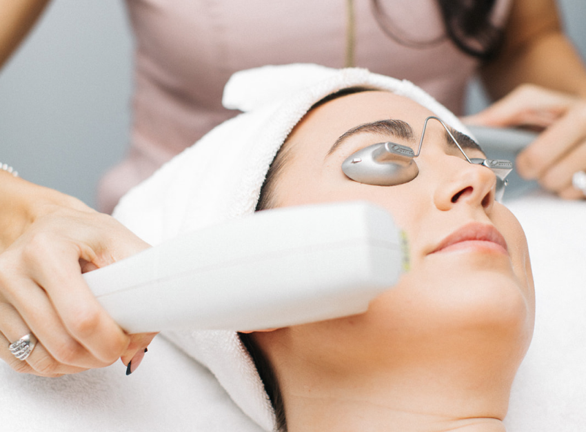 A woman receiving laser facial treatment, showcasing advanced skincare technology in a professional environment.